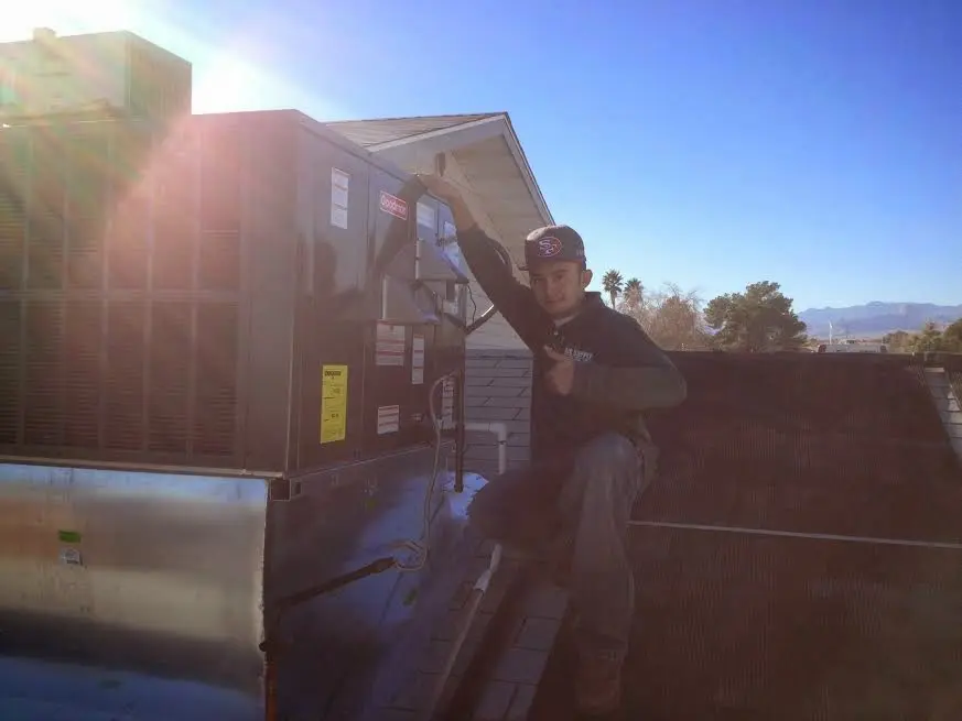 HVAC technician performing Air Duct Cleaning on a rooftop unit in Danvers